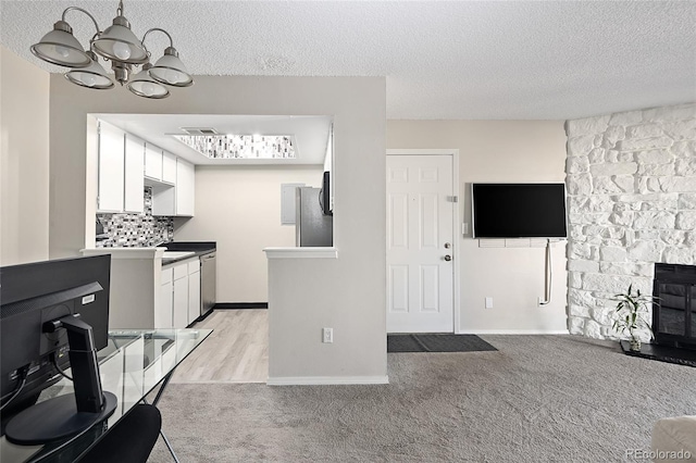 kitchen featuring light colored carpet, white cabinetry, a textured ceiling, and stainless steel appliances