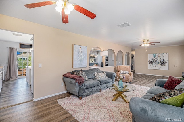 living area featuring a ceiling fan, baseboards, visible vents, and wood finished floors