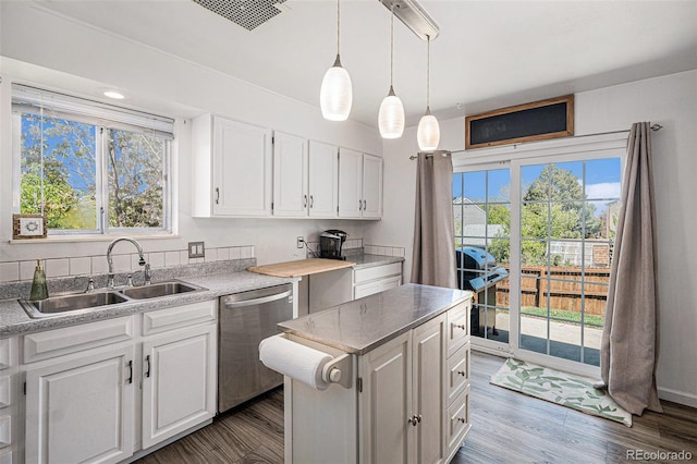 kitchen with stainless steel dishwasher, visible vents, white cabinets, a sink, and a wealth of natural light