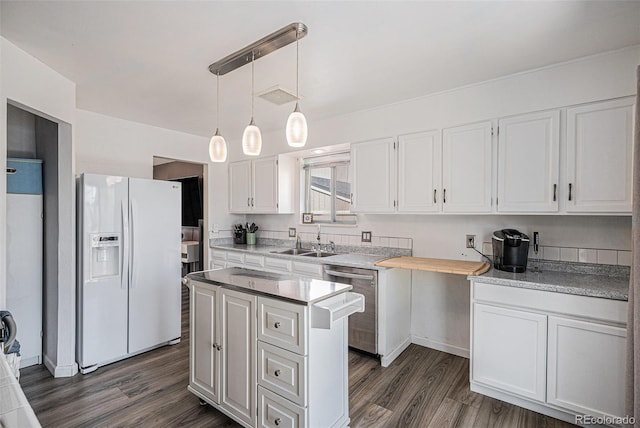 kitchen with stainless steel dishwasher, white refrigerator with ice dispenser, dark wood finished floors, a sink, and white cabinets