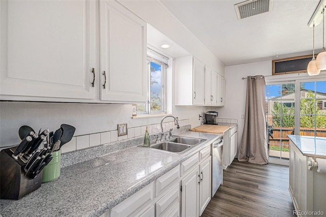 kitchen featuring white cabinets, visible vents, and a sink