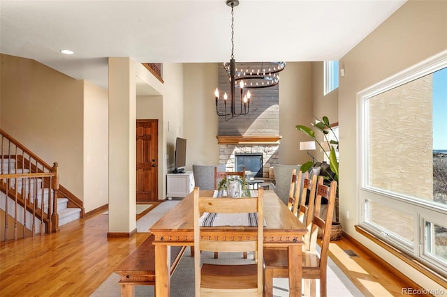 dining room featuring a notable chandelier, a fireplace, and light wood-type flooring