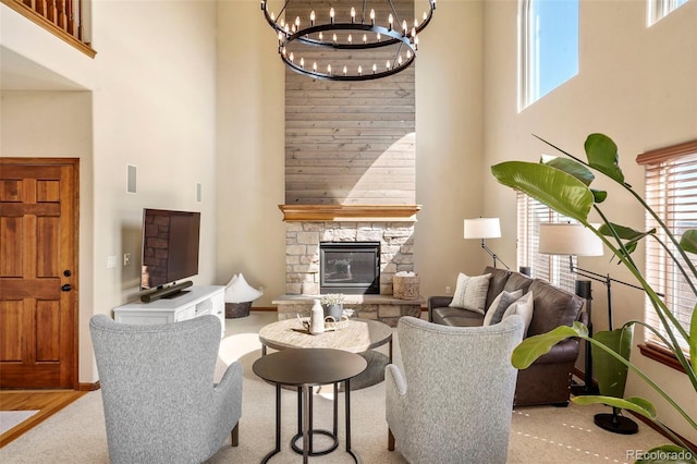 living room with a notable chandelier, a stone fireplace, and a high ceiling