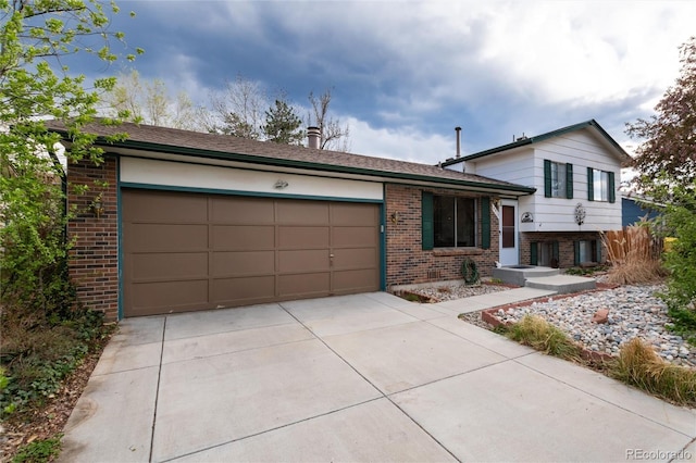 split level home with a garage, driveway, and brick siding