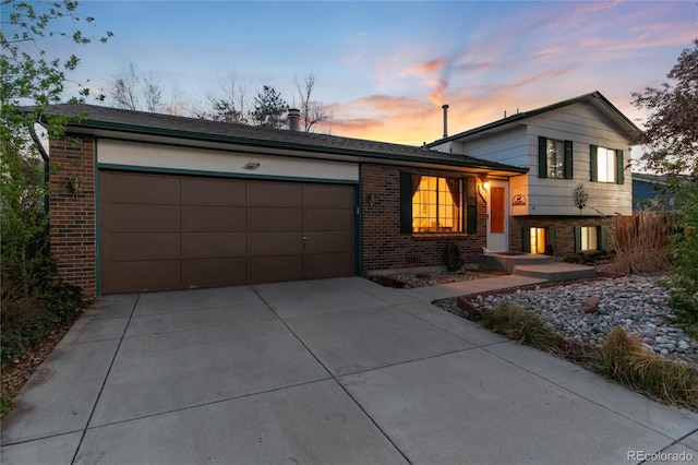 split level home with brick siding, an attached garage, and concrete driveway