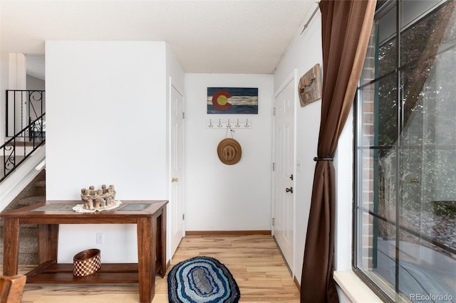 entryway featuring baseboards, stairs, and wood finished floors