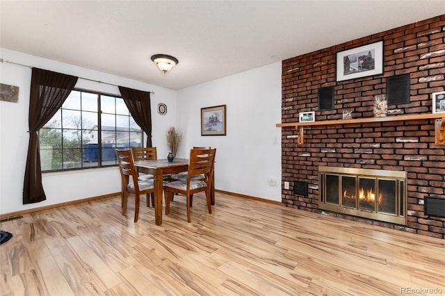 dining space featuring baseboards, a fireplace, and wood finished floors