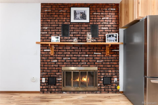 details featuring a textured ceiling, a fireplace, wood finished floors, baseboards, and freestanding refrigerator