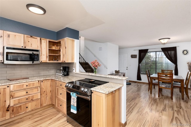 kitchen featuring light brown cabinetry, a peninsula, appliances with stainless steel finishes, and light wood finished floors