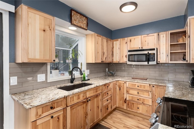 kitchen featuring a sink, light wood-style flooring, appliances with stainless steel finishes, and light brown cabinets