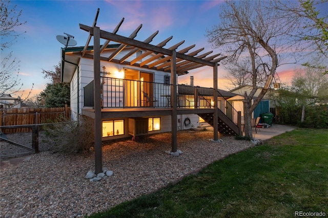 back of house at dusk with fence, a pergola, a deck, stairway, and a patio area