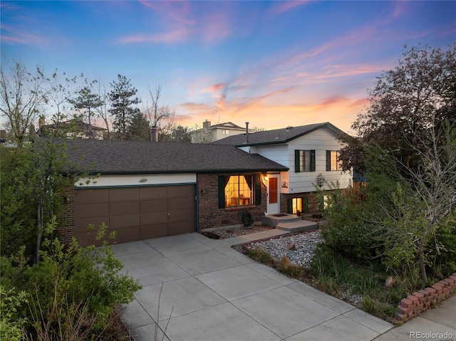 tri-level home with brick siding, a garage, and concrete driveway