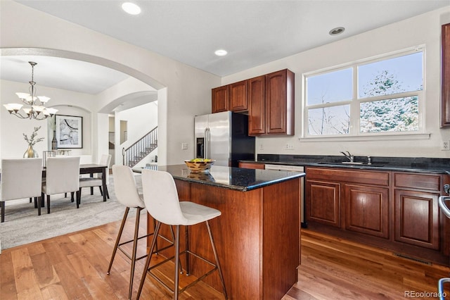 kitchen with a breakfast bar, a kitchen island, stainless steel fridge, and light wood-style floors