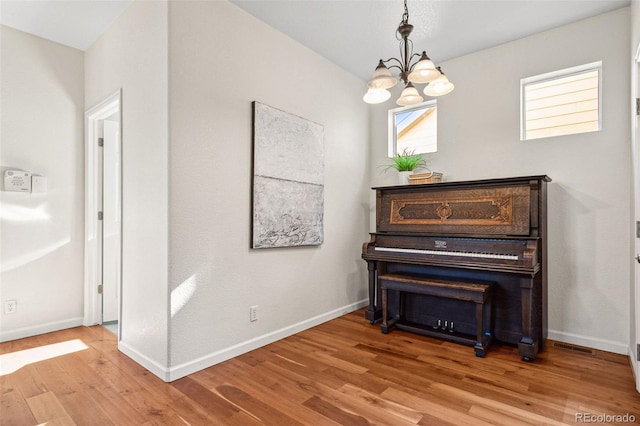 sitting room with light wood-style floors, baseboards, and a notable chandelier