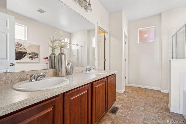 bathroom with visible vents, a sink, and a shower stall