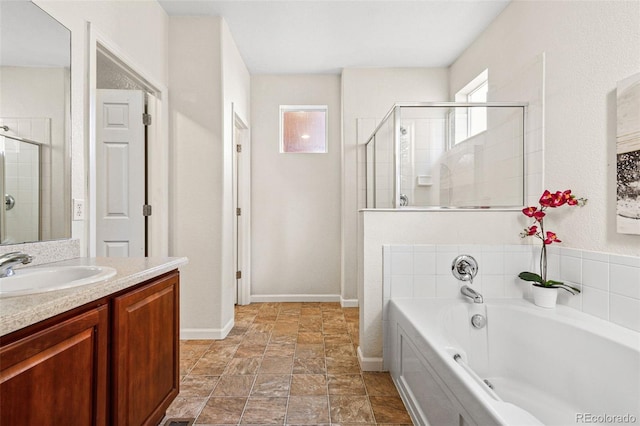 bathroom featuring vanity, a shower stall, a bath, and baseboards