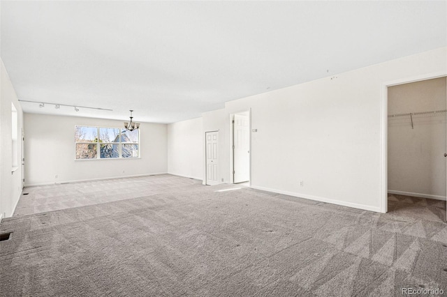 unfurnished living room featuring baseboards, a notable chandelier, visible vents, and carpet flooring