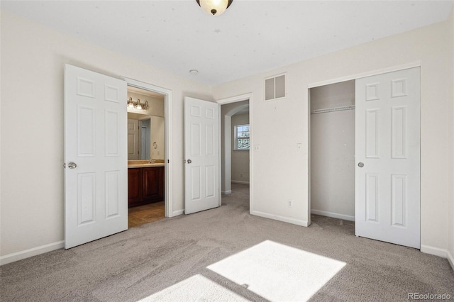 unfurnished bedroom with connected bathroom, light carpet, visible vents, baseboards, and a closet