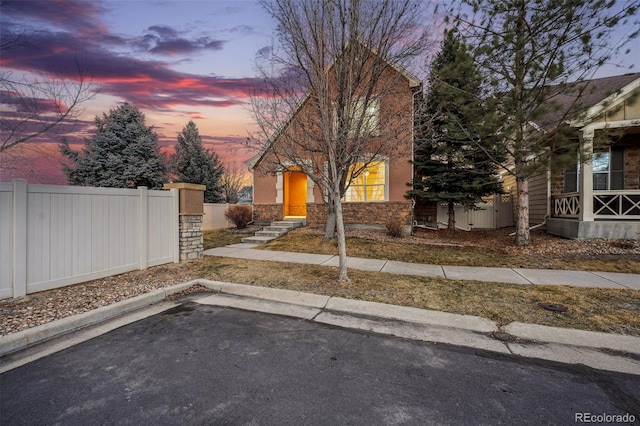 view of front of property featuring stone siding, fence, and stucco siding