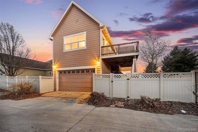 traditional home featuring fence private yard, a gate, a balcony, concrete driveway, and an attached garage