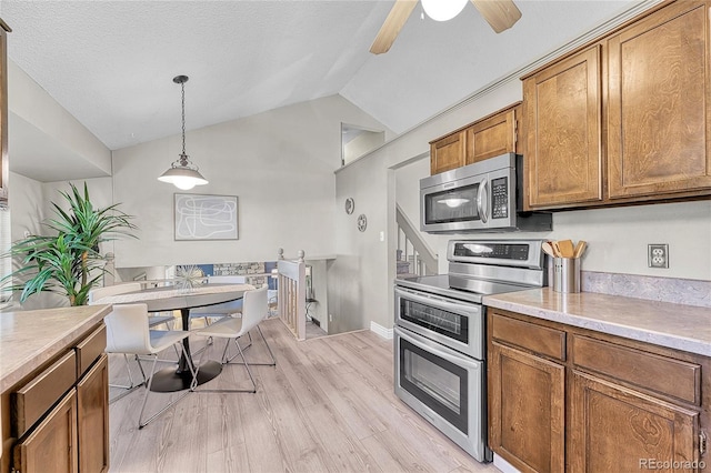 5543 S Kenton Ct, Englewood, CO 80111 - kitchen with appliances with stainless steel finishes, brown cabinetry, lofted ceiling, light wood-style floors, and light countertops