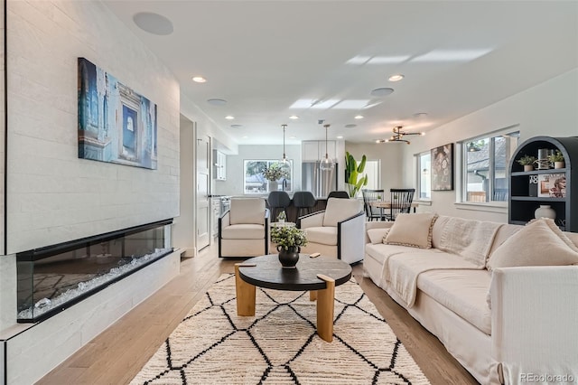 living room featuring light wood-type flooring and a large fireplace