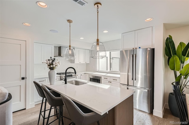 kitchen featuring light wood-type flooring, white cabinetry, a kitchen island with sink, and appliances with stainless steel finishes