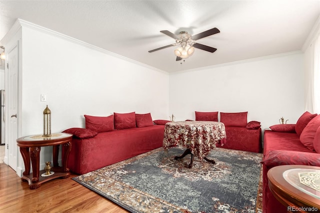 living room with ceiling fan, wood-type flooring, and ornamental molding