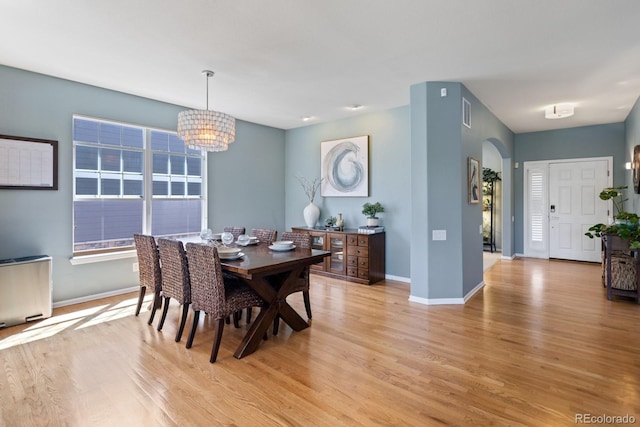 4515 W 107th Cir, Westminster, CO 80031 - dining area featuring light wood-style flooring, a chandelier, and arched walkways