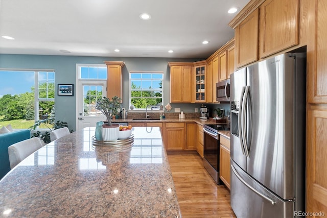 4515 W 107th Cir, Westminster, CO 80031 - kitchen featuring appliances with stainless steel finishes, recessed lighting, plenty of natural light, light wood finished floors, and glass insert cabinets
