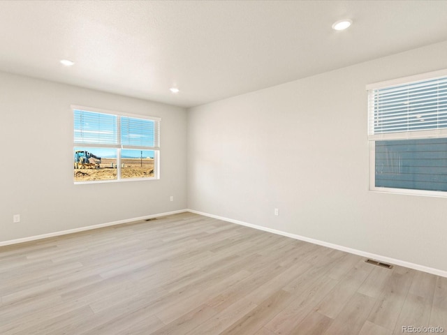 spare room featuring a healthy amount of sunlight and light hardwood / wood-style floors