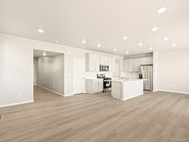 kitchen featuring light hardwood / wood-style floors, sink, appliances with stainless steel finishes, an island with sink, and white cabinets