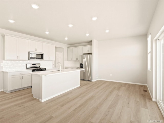 kitchen featuring white cabinetry, light hardwood / wood-style floors, an island with sink, stainless steel appliances, and sink