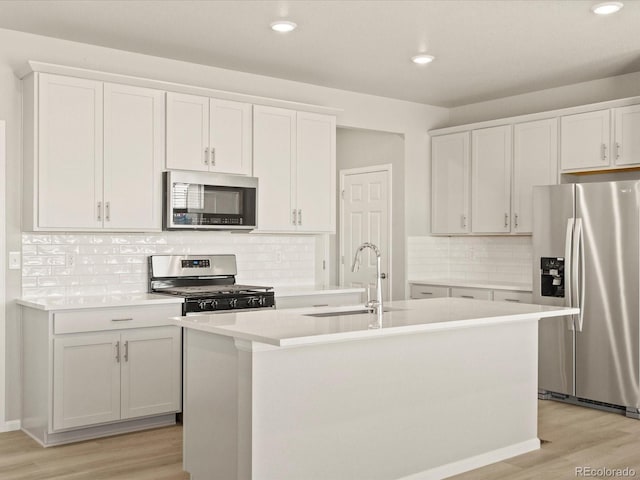 kitchen featuring appliances with stainless steel finishes, white cabinetry, and a center island with sink