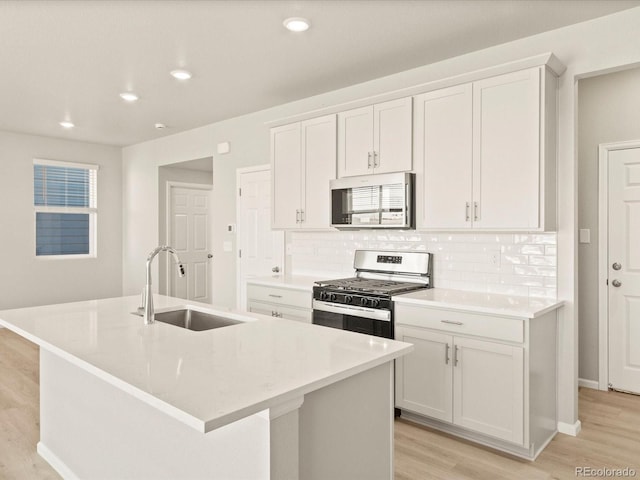 kitchen featuring white cabinetry, stainless steel appliances, a center island with sink, and sink