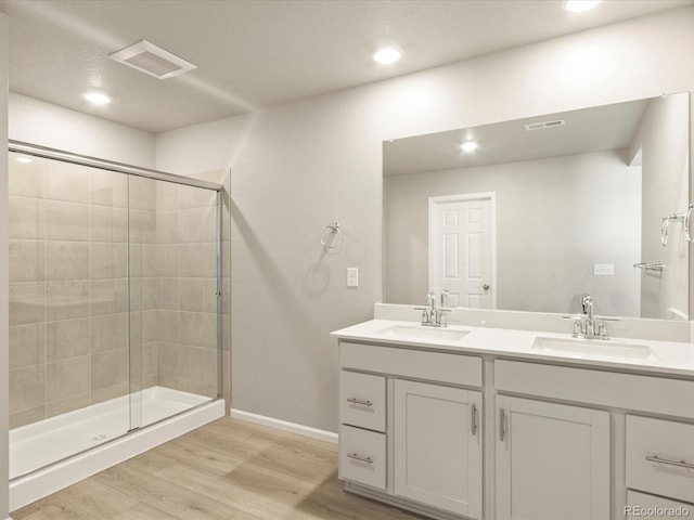 bathroom featuring hardwood / wood-style flooring, a shower with shower door, and vanity