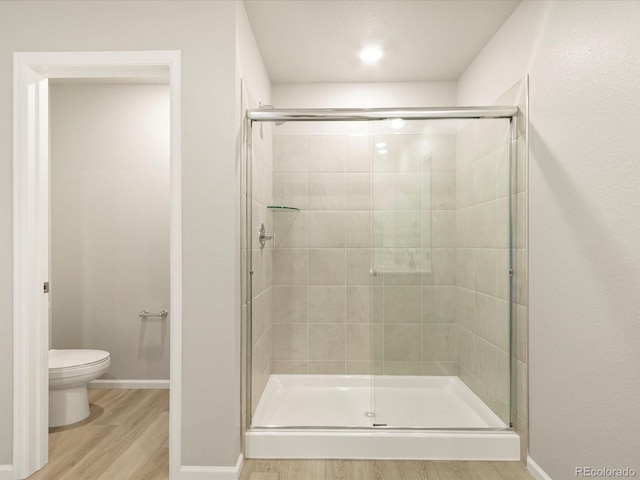 bathroom featuring toilet, wood-type flooring, and an enclosed shower