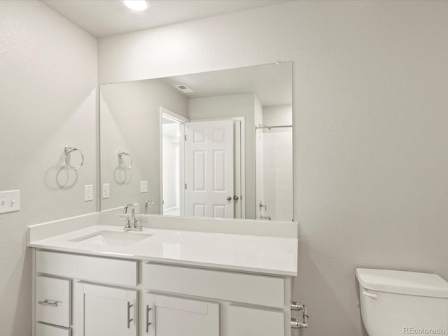 bathroom with walk in shower, vanity, and toilet