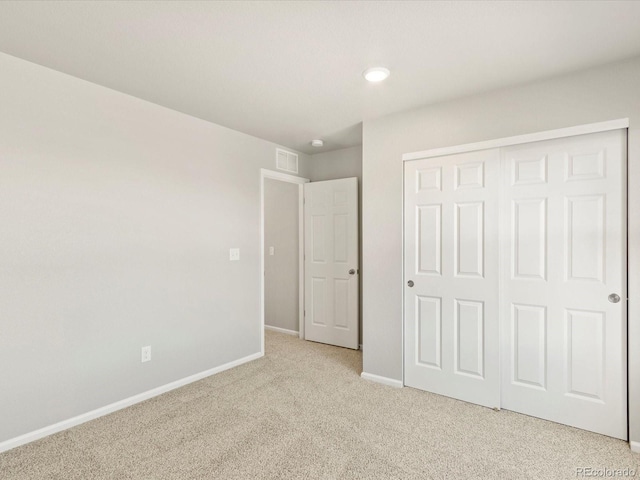 unfurnished bedroom with light colored carpet and a closet