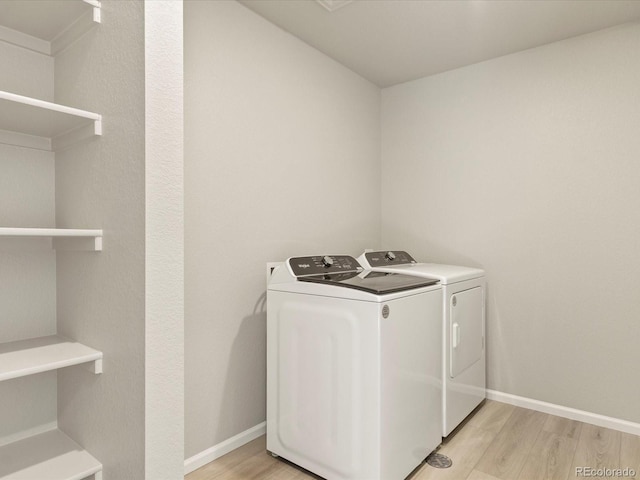 laundry area featuring washing machine and dryer and light hardwood / wood-style flooring