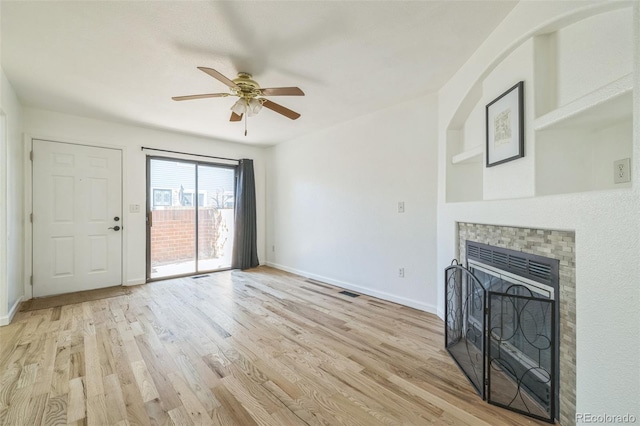 unfurnished living room featuring ceiling fan, a tile fireplace, and light hardwood / wood-style flooring