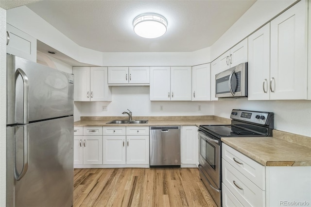 kitchen featuring sink, white cabinets, light wood-type flooring, and appliances with stainless steel finishes