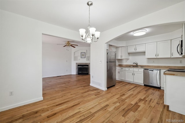 kitchen featuring wooden counters, ceiling fan with notable chandelier, decorative light fixtures, white cabinetry, and stainless steel appliances