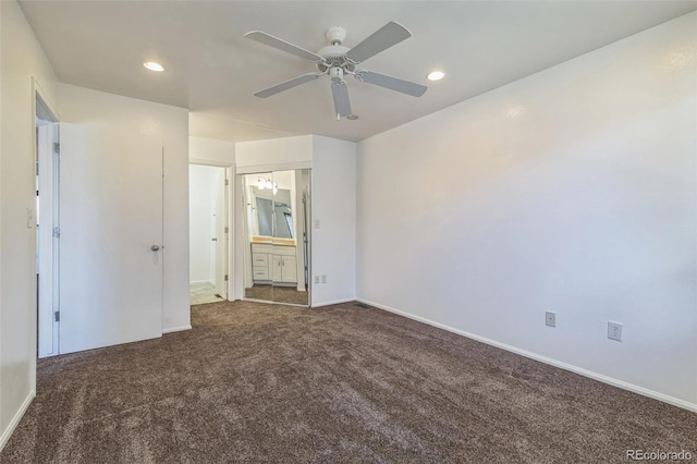 unfurnished bedroom featuring ensuite bathroom, ceiling fan, and dark colored carpet