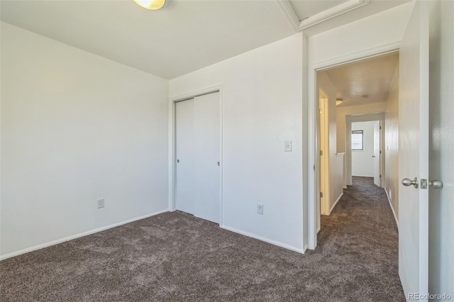 unfurnished bedroom featuring dark colored carpet and a closet