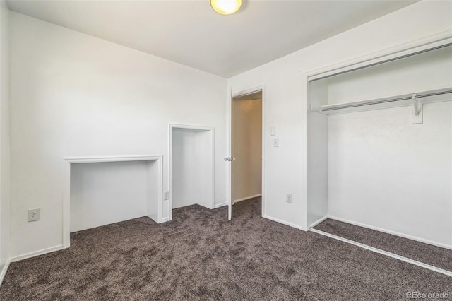 unfurnished bedroom with dark carpet and a closet