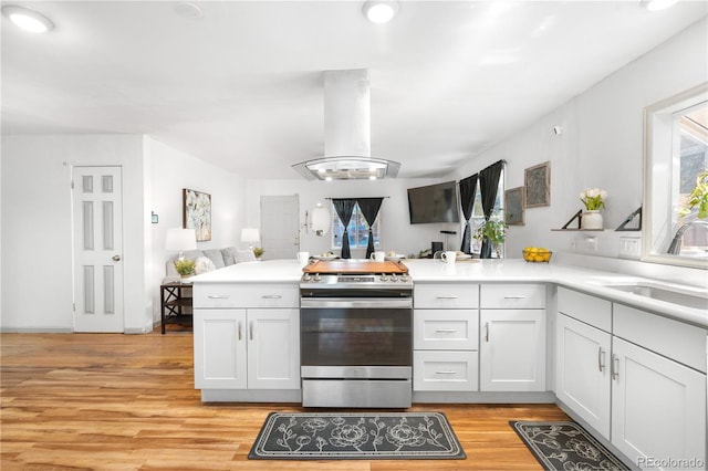 935 S Pecos Way, Denver, CO 80223 - kitchen with stainless steel electric range oven, island exhaust hood, a peninsula, light wood-type flooring, and light countertops
