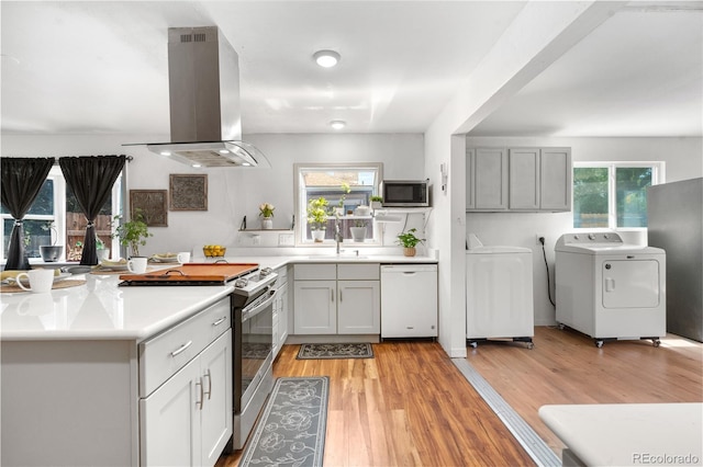 935 S Pecos Way, Denver, CO 80223 - kitchen featuring stainless steel appliances, island range hood, washing machine and clothes dryer, and healthy amount of natural light