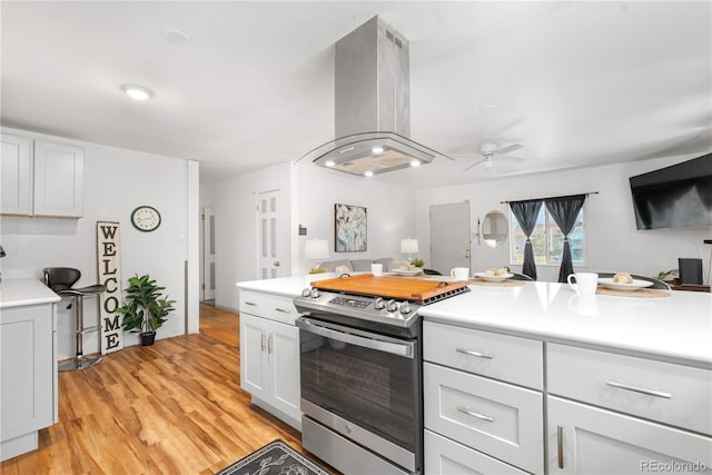 935 S Pecos Way, Denver, CO 80223 - kitchen featuring stainless steel range with gas cooktop, island range hood, light countertops, and ceiling fan
