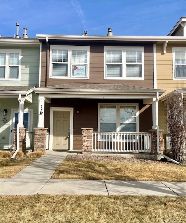 townhome / multi-family property with a porch and stone siding